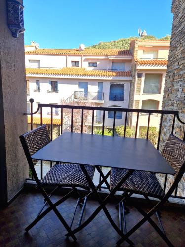 une table noire et des chaises sur un balcon dans l'établissement La Bourboule, à Collioure