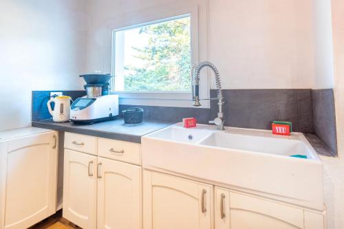 a kitchen with a white sink and a window at Maison 250m plage - grand jardin in L'Ile d'Yeu