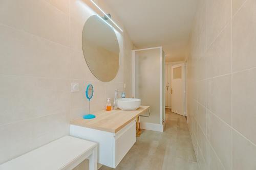 une salle de bain blanche avec un lavabo et un miroir dans l'établissement Porte des Bès T2 dans Intra-muros plage à 10 m, à Saint-Malo