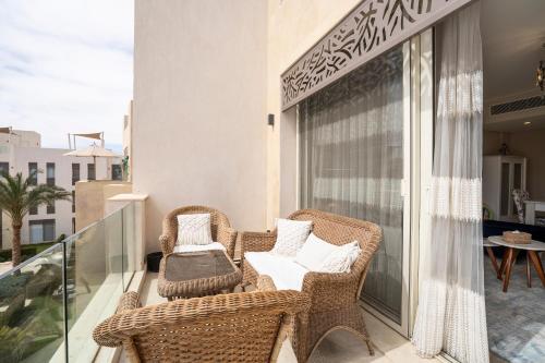 a balcony with two wicker chairs and a table at Mangroovy Seafront condo - Great Kite Surfing in Hurghada