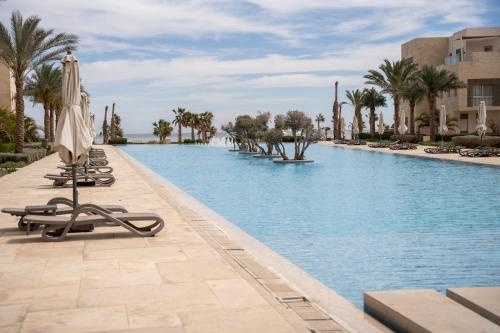 a pool at a resort with chairs and an umbrella at Mangroovy Seafront condo - Great Kite Surfing in Hurghada