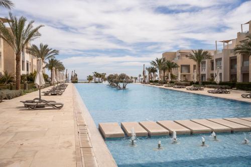 a large swimming pool with palm trees and buildings at Mangroovy Seafront condo - Great Kite Surfing in Hurghada