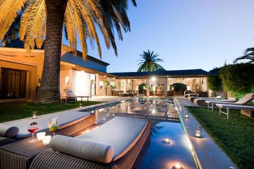 an outdoor pool with lounge chairs and a palm tree at Le Pre de la Mer in Saint-Tropez