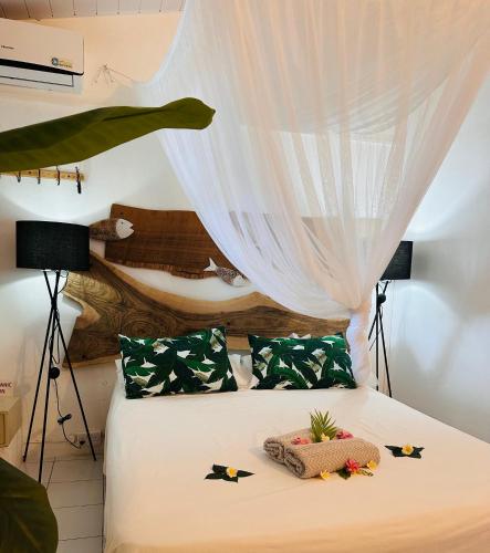 a bedroom with a bed with a curtain over it at Residence Ma Vie Là Ltee in Le Morne