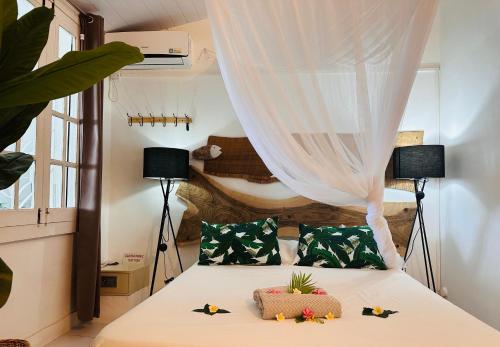 a bedroom with a bed with a curtain and two lamps at Residence Ma Vie Là Ltee in Le Morne