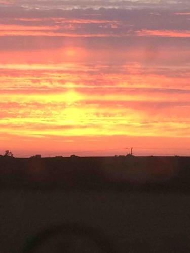 a sunset over a field with the sky at The Den at Husthwaite Gate in Husthwaite