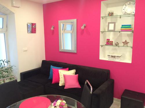 sala de estar con sofá negro y pared rosa en Apartment Dea II, en Split