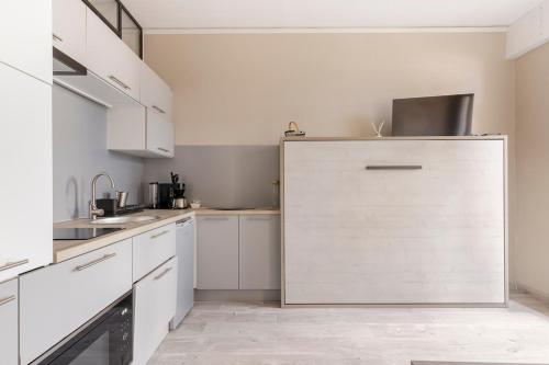 La cuisine est équipée de placards blancs et d'un grand réfrigérateur. dans l'établissement Studio Toulouse centre Matabiau, à Toulouse