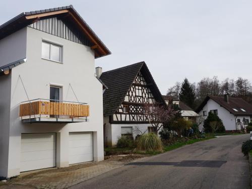a white house with a wooden balcony on a street at Haus Redi in Sasbach in der Ortenau