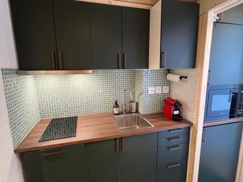 une cuisine avec des armoires vertes et un évier dans l'établissement Studio 4 pers. proche pistes et commerces, balcon, animaux acceptés - FR-1-502-417, à Tignes