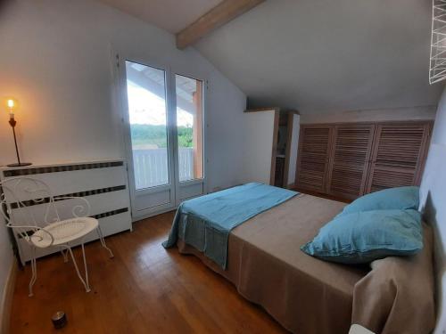 une chambre avec un lit et une grande fenêtre dans l'établissement Villa de Campagne au bord de l'Adour, à Saint-Laurent-de-Gosse