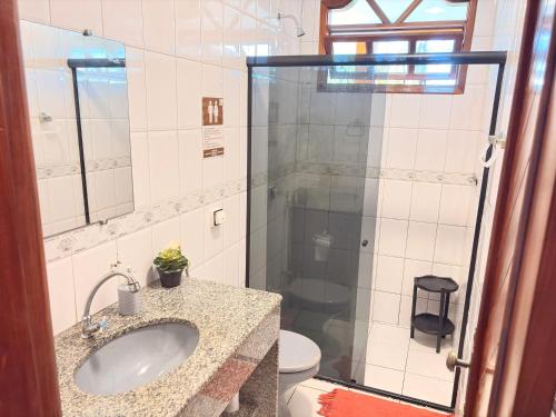a bathroom with a sink and a glass shower at Terra do Sol Pousada e Hostel in Porto Seguro
