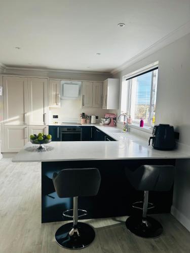 a kitchen with a counter and two bar stools at Atlantic View - Sauna and Sunsets in Isle of Lewis