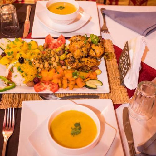 a table with a plate of food and a bowl of soup at Merzouga Horizon Luxury Camp in Merzouga