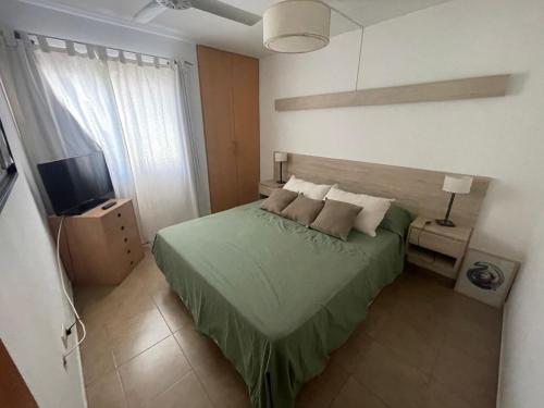 ein Schlafzimmer mit einem grünen Bett und einem Fernseher in der Unterkunft Casa con pileta Aeropuerto Circunvalación Kempes Quorum Siglo 21 in Cordoba