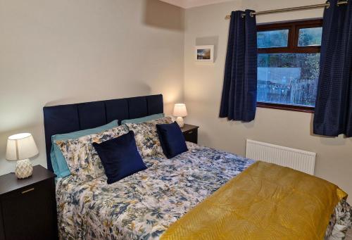 a bedroom with a bed with blue pillows and a window at Midtown Apartment in Ardara