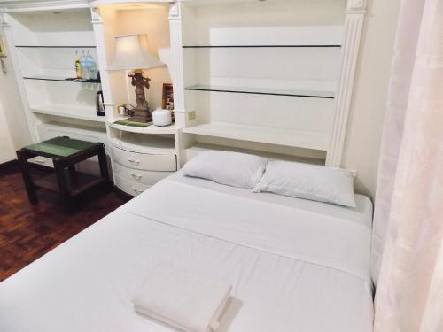 マニラにあるPhoy Guest House Manilaの白いベッドとテーブルのある寝室