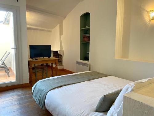 a bedroom with a bed and a desk with a television at La Villageoise in Aups