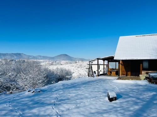 a house covered in snow next to a building at Log cabin in Sejdanovići