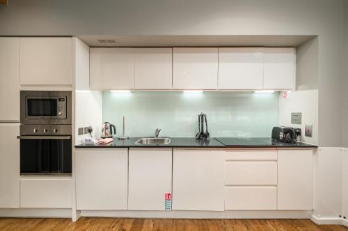 a white kitchen with a sink and a microwave at Destiny Scotland -The Malt House Apartments in Edinburgh