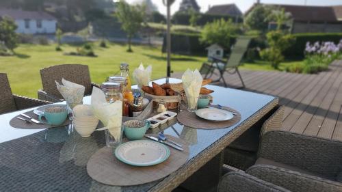 une table avec des assiettes de nourriture et des paniers de pain dans l'établissement Vieille Fermette BnB chambre prive, à Waben