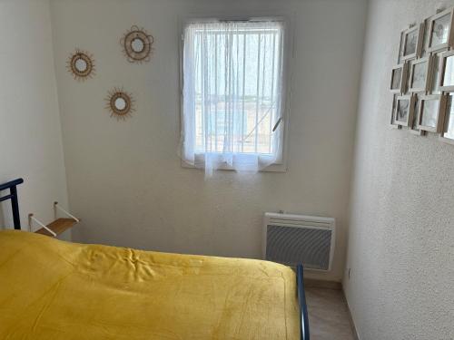 a bedroom with a yellow bed and a window at T2 50m PLAGE BARCARES PORT RDC in Le Barcarès