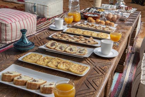 梅尔祖卡Shining Luxury Camp的桌子上放着糕点和橙汁托盘