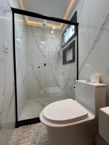 a bathroom with a toilet and a glass shower at Suíte Praia Seca com ar condicionado in Araruama