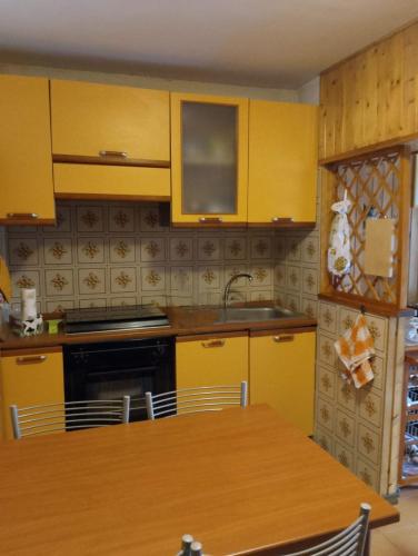 a kitchen with yellow cabinets and a wooden table at Marconi relax in Filettino Graziani