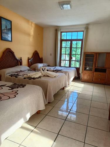 a room with three beds and a window at HOTEL CAMELINAS AREA BLANCA in Pátzcuaro