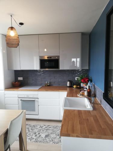 - une cuisine avec des placards blancs, un évier et une table dans l'établissement Logement et parking privé proche centre, à Reims