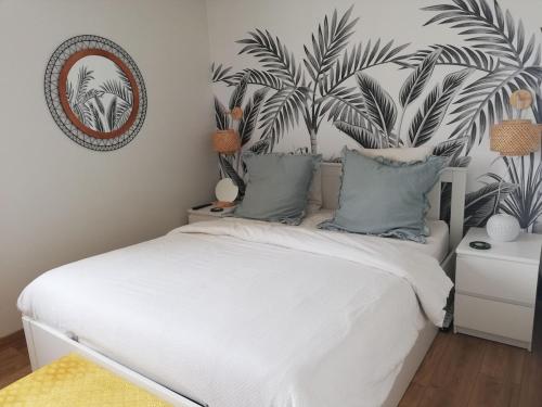 - une chambre dotée d'un lit blanc et d'une fresque murale représentant la plante dans l'établissement Logement et parking privé proche centre, à Reims