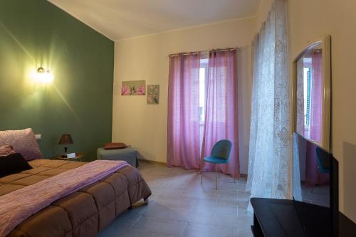 a bedroom with a bed and pink curtains and a tv at CasaMilla in Campobasso