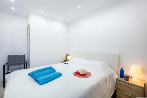 Una cama blanca con sombrero y una toalla azul. en Chic apartment with great terrace, en Playa de las Américas