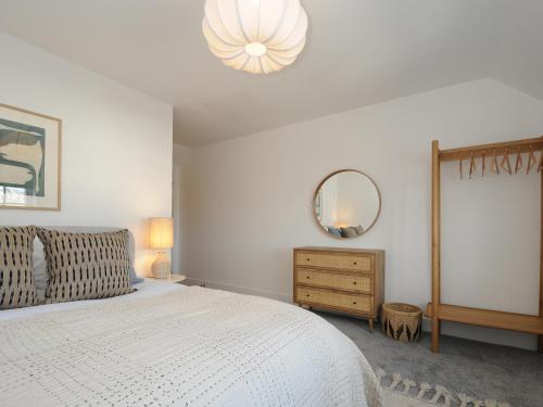 a bedroom with a white bed and a mirror at Wharfside in Penzance