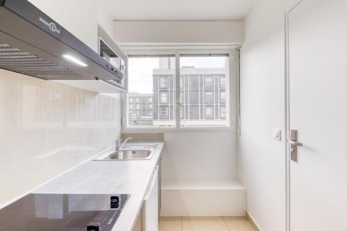 une cuisine blanche avec un évier et une fenêtre dans l'établissement Studio douillet 6, à Sarcelles