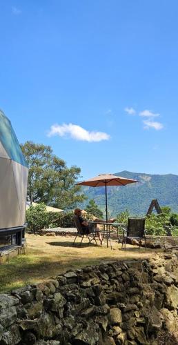a table with an umbrella and two chairs and a table with at Chalé Refugio da Pedra SP in São Bento do Sapucaí