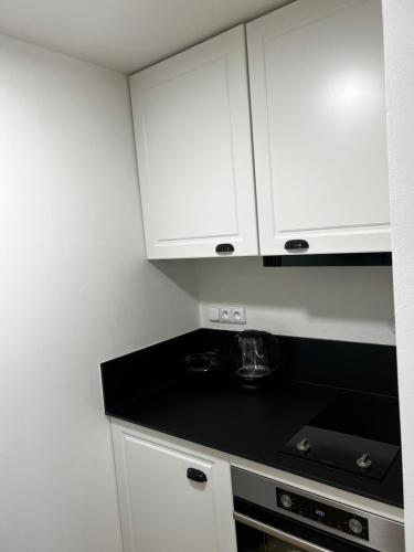 a kitchen with white cabinets and a black counter top at Bedřichov 1717 in Bedřichov