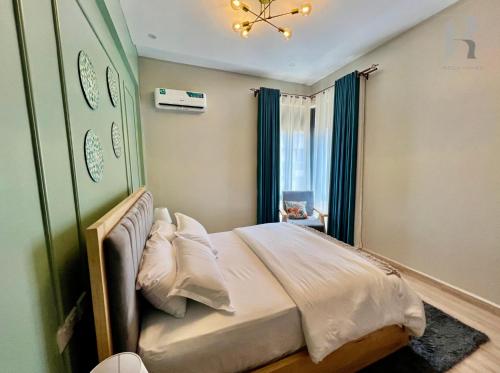 a bedroom with a large bed with a chandelier at Rozy homes, Garuga Entebbe, next to lake Victoria in Wakiso