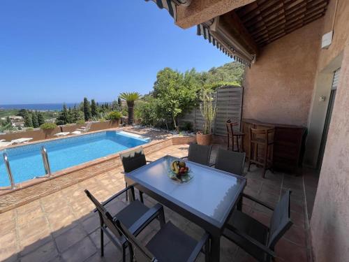 un patio avec une table et des chaises et une piscine dans l'établissement Mas lou beu, au Lavandou