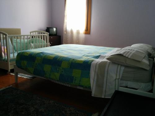 a bedroom with a bed with a crib and a window at Holiday Home La Moranda in San Fior di Sopra