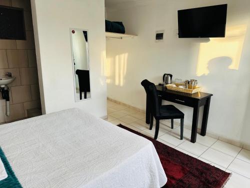 a bedroom with a bed and a desk with a sink at Township Lodge -Seshego in Polokwane