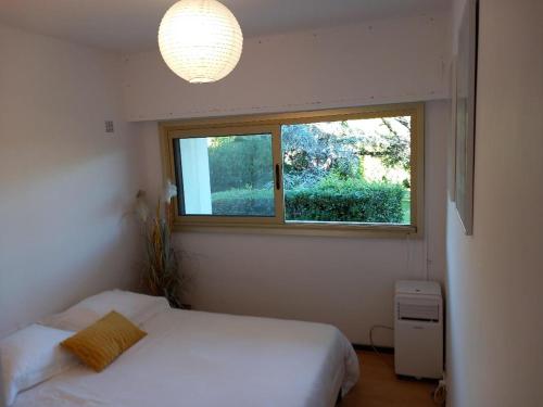 une chambre avec un lit blanc et une fenêtre dans l'établissement Studio et chambre sur jardin et mer, à Cannes