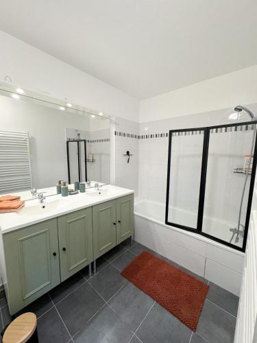 La salle de bains blanche est pourvue de 2 lavabos et d'une baignoire. dans l'établissement T3 duplex with garden, à Arpajon-sur-Cère