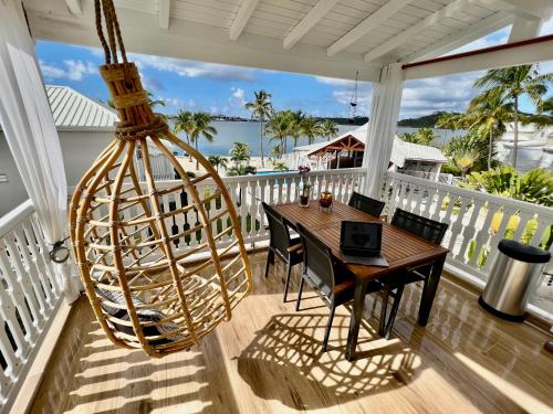 a porch with a wooden table and a swing at Duplex JUNGLE BLEUE Terrasse vue mer incroyable in Marigot