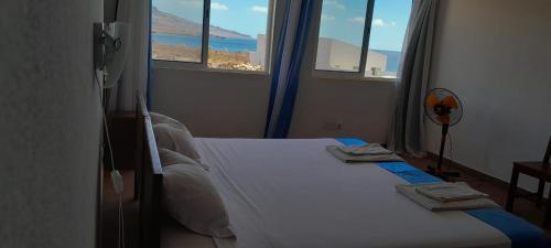 a bedroom with a bed with a view of the ocean at Cacimba Sunset Lodge in Tarrafal