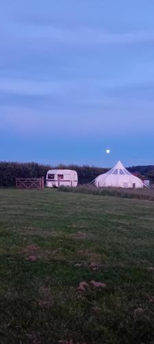 un campo con una tienda y un remolque blanco en Stargazer Bell Tent, en Northrepps