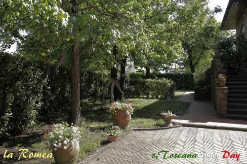 a garden with flower pots and trees and a walkway at La Romea in Altopascio