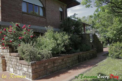 a brick retaining wall in front of a house with flowers at La Romea in Altopascio