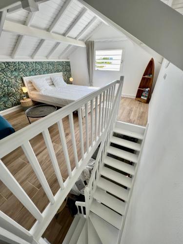 a white room with a bed and a staircase at Duplex JUNGLE BLEUE Terrasse vue mer incroyable in Marigot